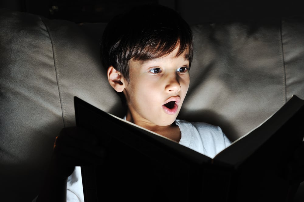Kid reading book, light in darkness